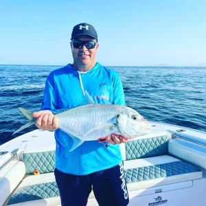 Happy guest holding trevally catch on fishing charter in Fujairah UAE