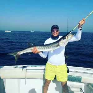 Smiling guest holding barracuda caught on fishing charter in Fujairah UAe