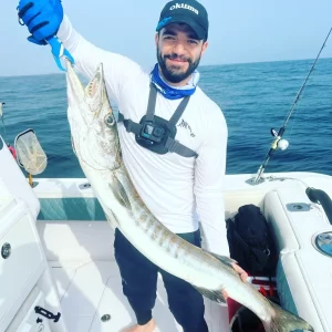 Guest showing off barracuda catch on fishing charter in Fujairah UAE