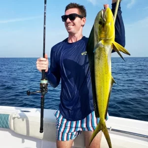 Guest holding a dorado and fishing rod on deep sea fishing charter in Fujairah UAE