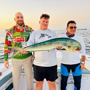 Grandslam captain Dante holding a dorado with two guest standing next to him on a deep sea fishing charter in Fujairah UAE