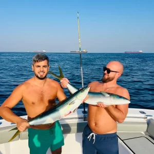 Two guests each holding a rainbowfish caught on fishing charter in Fujairah UAE
